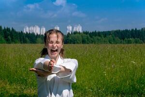 teenage girl training karate kata outdoors, performs nukite tsuki strike with kiai scream photo