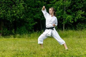 teenage girl training karate kata outdoors, performs age-uke rising or upward block photo