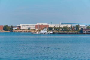 towboat pushes dry bulk cargo barge on the river past the industrial landscape photo