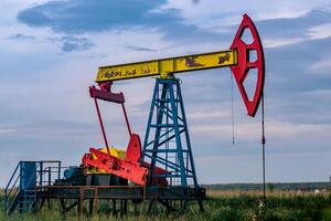 pumpjack operating at an oil well in field outdoors photo