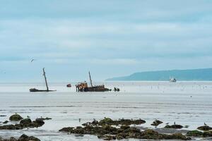 seascape with a shipwreck in the foreground and a small fishing vessel at sea in the background photo