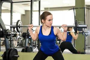 young woman performs the exercise squat with barbell photo