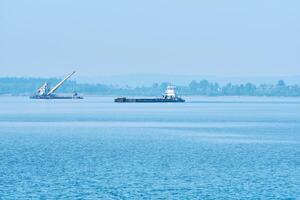 foggy river water landscape with cargo barge and dredger in the background photo