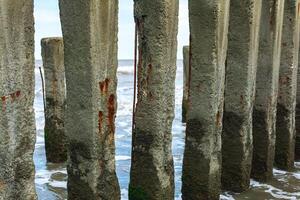 old groyne made of concrete piles close-up against the backdrop of a stormy sea photo