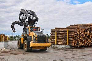 grapple loader in the lumber yard of a woodworking plant photo