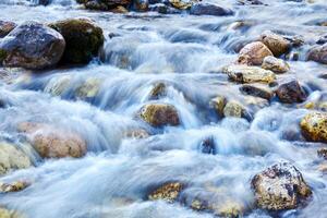 background - a mountain stream in a rocky channel, the water is blurred in motion photo