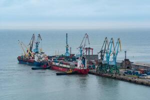 container ship is moored with the help of tugboats to a cargo berth photo