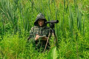 ornithologist records the results of the observations while standing among the tall grass in the wetland photo