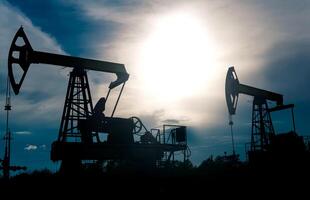 silhouettes of pumpjacks on an oil wells against the background of an alarming sky photo