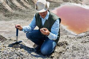 hombre geólogo examina un rock muestra en un Desierto zona foto