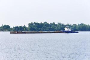 pusher tug pushes dry bulk cargo barge with sand on the river photo