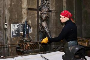 mujer metal artista a trabajo en taller utilizando corte de metal Sierra foto