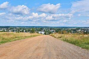 dirt road leads to the village in the background photo