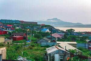 landscape of the town of Yuzhno-Kurilsk on the island of Kunashir with a view of the sea bay and the Mendeleev volcano in the distance photo