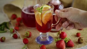 refreshing cool strawberry lemonade with lemon, ice and mint in a glass on a wooden table video