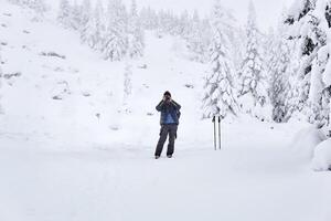 man traveler photographs nature in the winter mountains photo