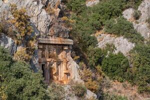 antiguo tallado en piedra tumba en el ladera de la montaña en myra licio demré, Turquía foto