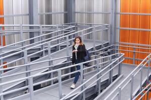 young woman looks at her watch as she climbs the winding ramp of a covered overpass photo