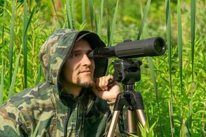 man ornitologist makes observations in the wild with a spotting scope photo