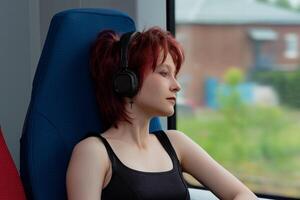 girl rides on a commuter train and looks out the window at a natural landscape blurred in motion photo