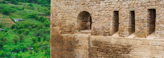 fragment of the wall of a medieval castle, behind which the faubourgs are visible, Naryn-Kala citadel in Derbent photo