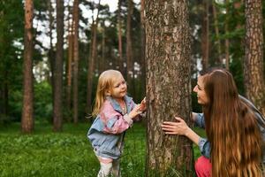 woman playing with a child in the forest, hiding behind a tree photo