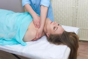 hermosa joven mujer disfrutando un masaje de el cara y cuello zona en el spa salón foto