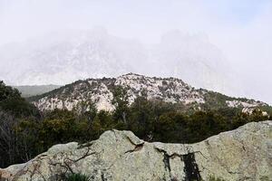 mountain range in the fog is barely visible behind the rocks on the foreground photo