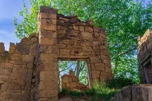 ruins of an old stone house under a tree in the historical abandoned village of Gamsutl in Dagestan photo