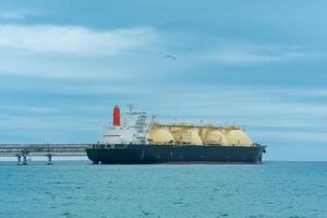 licuado natural gas portador petrolero durante cargando a un lng costa afuera Terminal, en el distancia el petróleo exportar terminal es visible en el mar foto