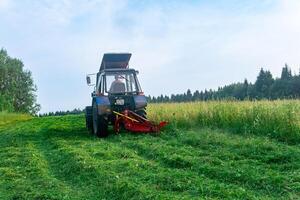 tractor con un montado cortacésped corta prado herbáceas foto