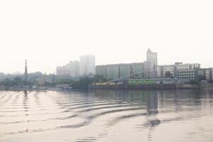 urban water landscape - industrial city and cargo port in fog on the bank behind the river photo