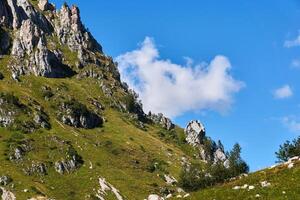 pie de un rocoso montaña con caliza acantilados, descuidado con verde césped foto