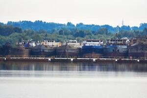 old cargo ships, prepared for disassembly and cutting into metal, in the river harbor photo