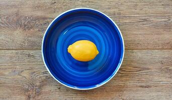 bright yellow lemon on a blue plate on a wooden tabletop photo