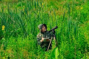 wildlife explorer records the results of the observations while standing among the tall grass in the wetland photo