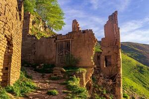 ruins of house in the abandoned village of Gamsutl overlooking the mountains photo