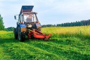 tractor with a mounted mower mows meadow forbs photo