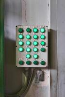 shabby control panel for some industrial processes with luminous buttons on the wall in the workshop photo