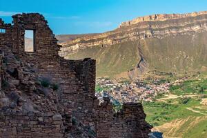 walls of abandoned houses on a mountain cliff in the ghost village of Gamsutl in Dagestan, on the opposite side of the valley the inhabited village of Chokh is visible photo