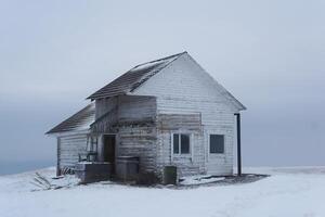 antiguo de madera casa en parte superior de un montaña en un Nevado invierno paisaje foto