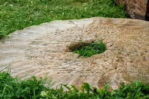 old shattered millstone lies on the grass somewhere in the countryside photo