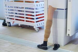 human leg prosthesis stands against the pool wall while its wearer swims photo