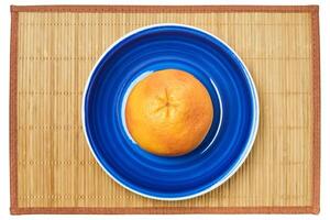 rosy yellow grapefruit on a blue plate on a cane place mat photo