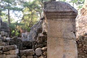 half-erased antique inscription on a stone among the ruins of the ancient city of Phaselis, Turkey photo