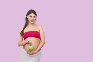 young pregnant woman holds a green apple photo