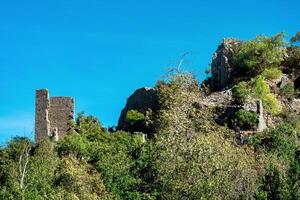 ruins of fortress walls on wooded mountain slopes in the antique city of Olympos, Turkey photo