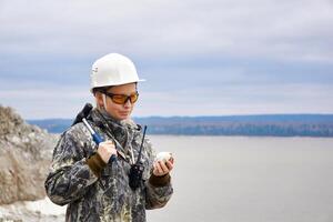 mujer geólogo examina un mineral muestra a el borde de el cantera foto