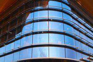 fragment of the glazed facade of a modern building with the sky reflected in it photo