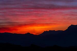 puesta de sol en el montañas, noche paisaje con brillante cielo foto